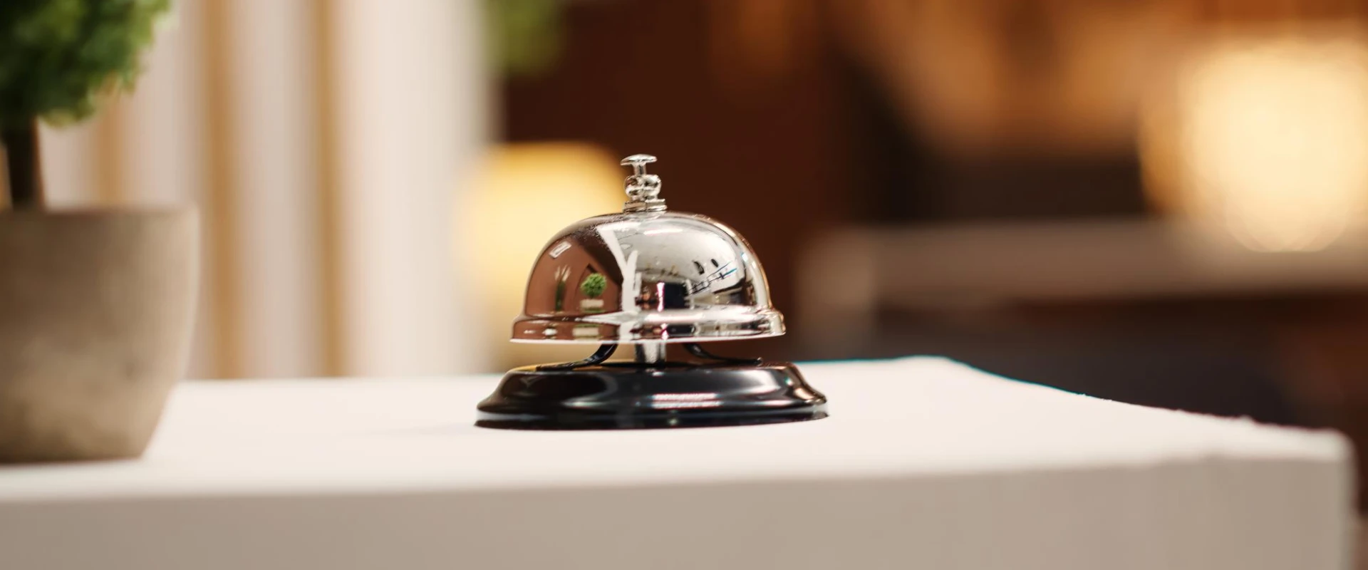 Cloche de réception en métal sur un comptoir blanc.