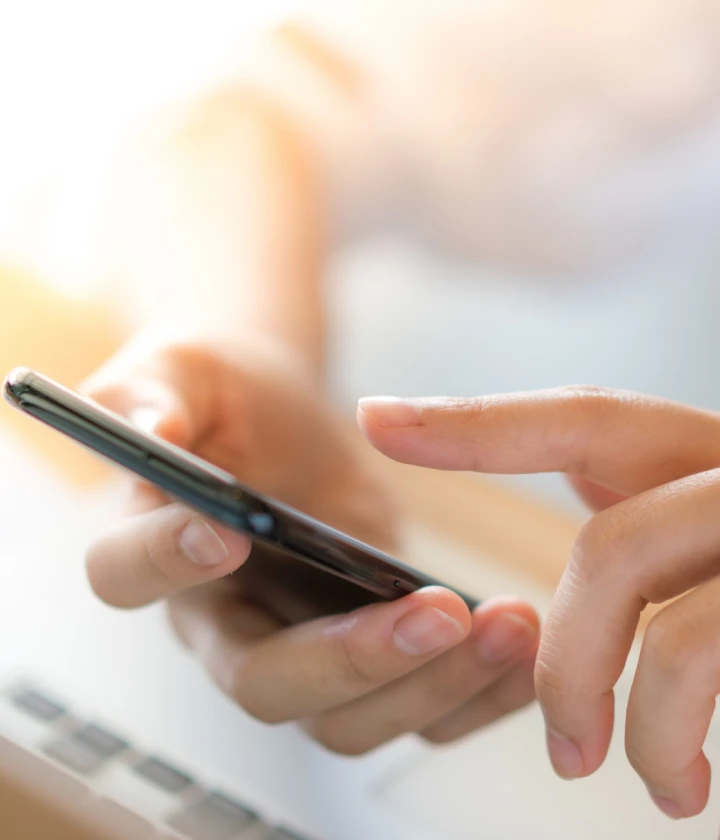 Main tenant un smartphone et touchant l'écran.