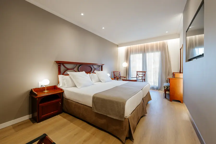 Habitación de hotel moderna con cama doble y ventanal.