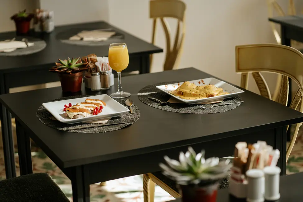 Platos servidos en mesa de restaurante elegante con jugo y plantas decorativas.