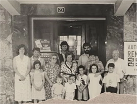 foto antigua con grupo de personas posando frente a un edificio.