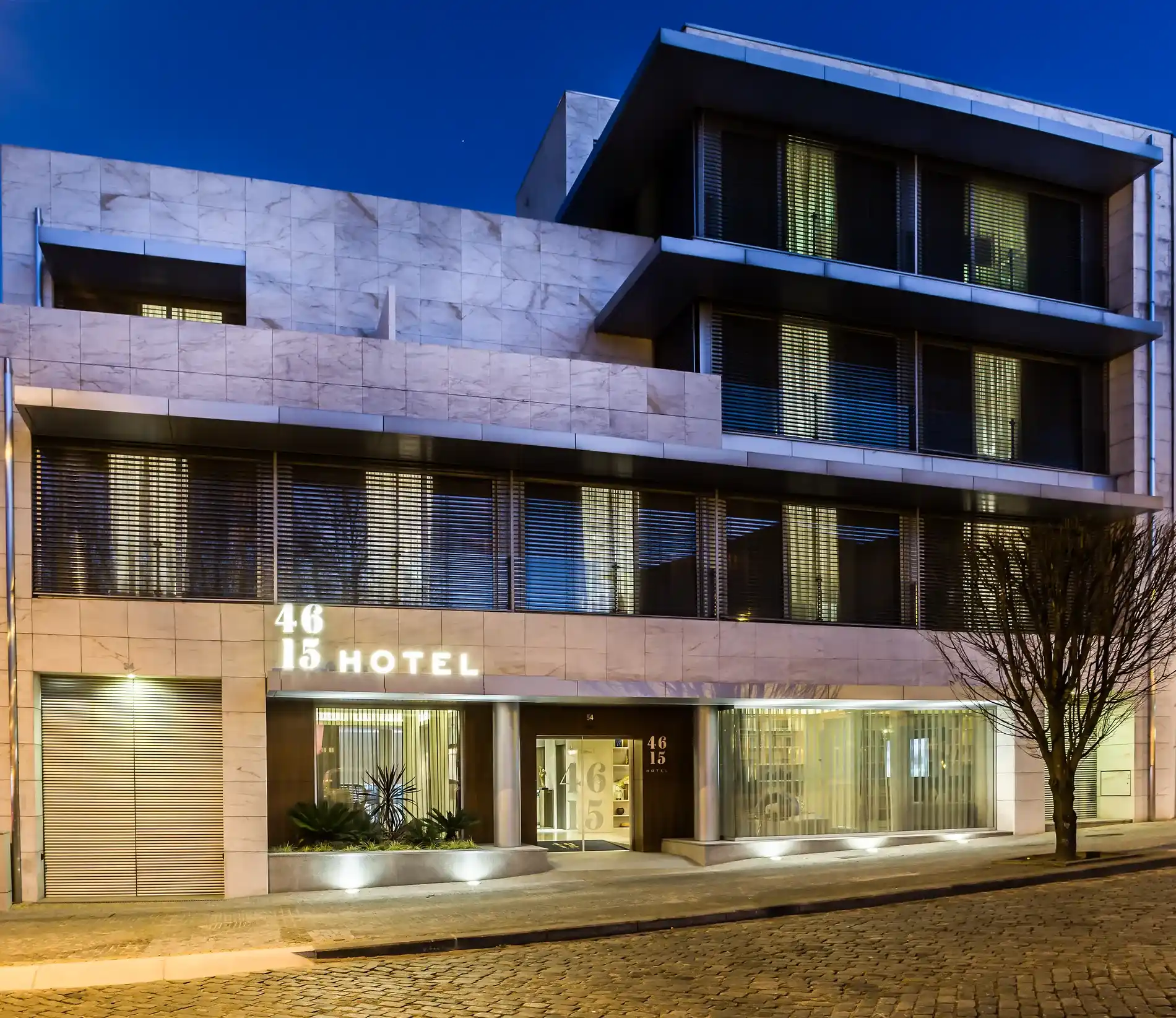 Fachada de hotel moderno iluminado &agrave; noite, com design contempor&acirc;neo.