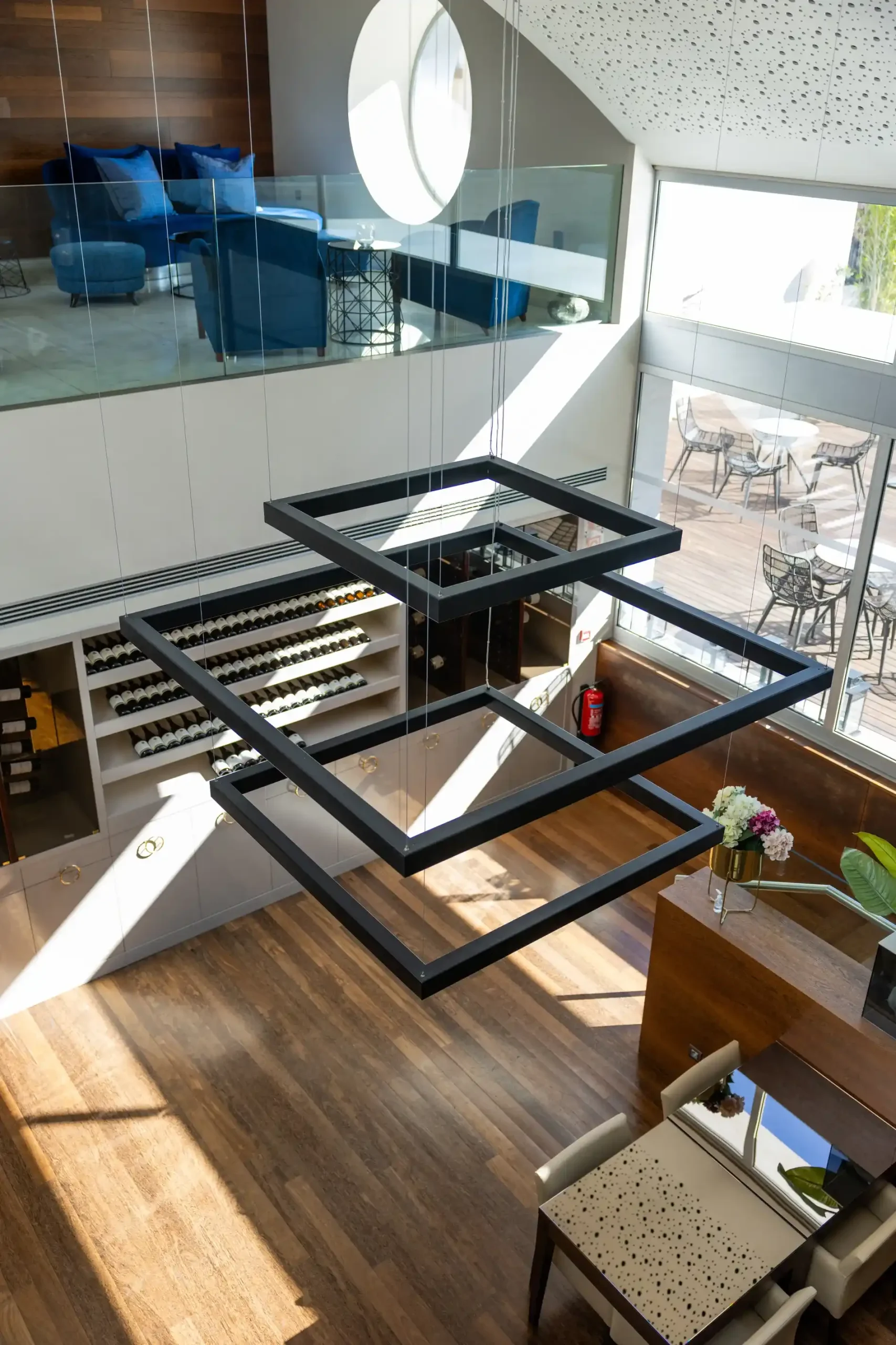 Ambiente moderno com lumin&aacute;ria geom&eacute;trica e adega. M&oacute;veis em tons de azul e madeira.