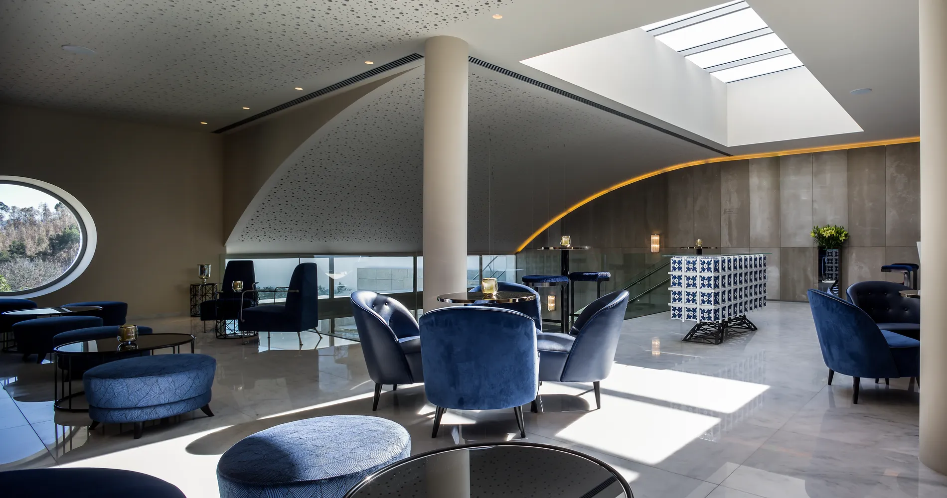 Sala moderna com poltronas azuis e luz natural.