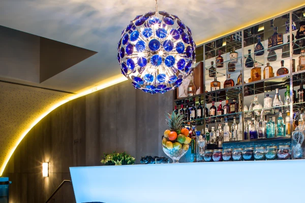 &Aacute;rea de bar moderna com balc&atilde;o iluminado e lumin&aacute;ria azul.