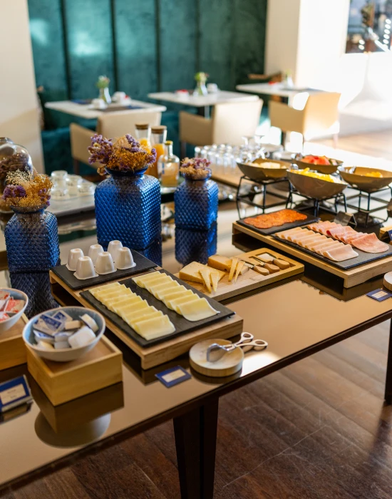 Mesa de caf&eacute; da manh&atilde; com queijos, frios, frutas e decora&ccedil;&atilde;o colorida.