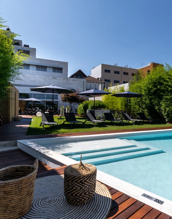 &Aacute;rea de piscina moderna com espregui&ccedil;adeiras e guarda-s&oacute;is pretos.