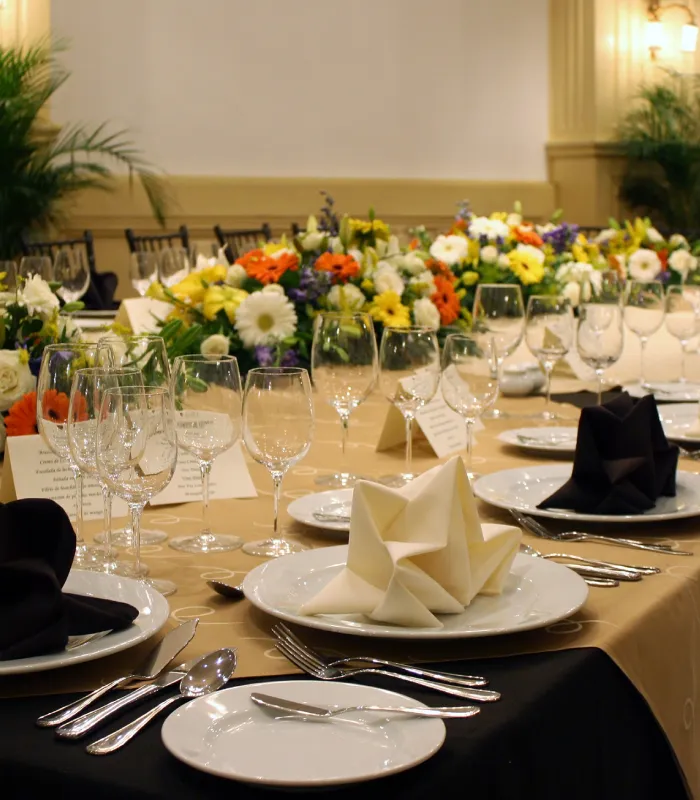 Elegant dining table setup with folded napkins, wine glasses, and a vibrant flower arrangement.