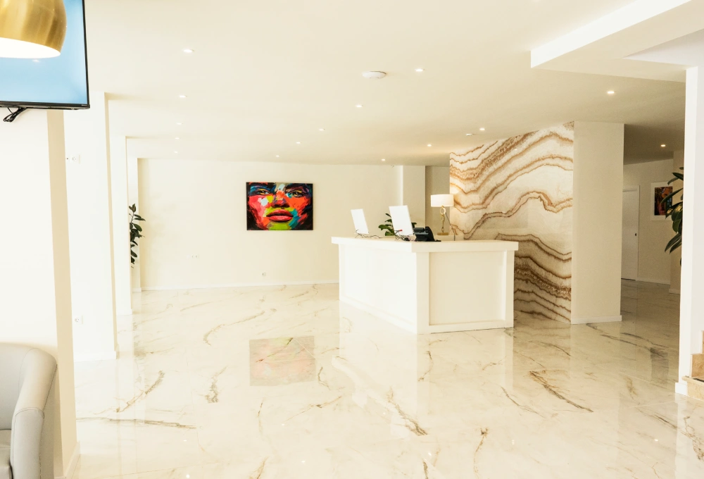 Recepción de hotel moderna con suelos de mármol y cuadro colorido en la pared.