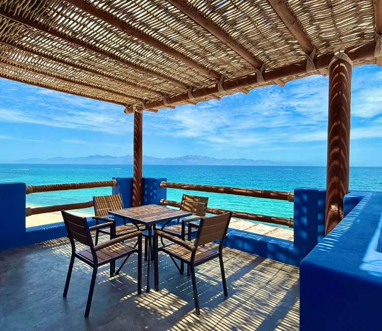 Terraza con sombra y vista al mar azul y cielo despejado.