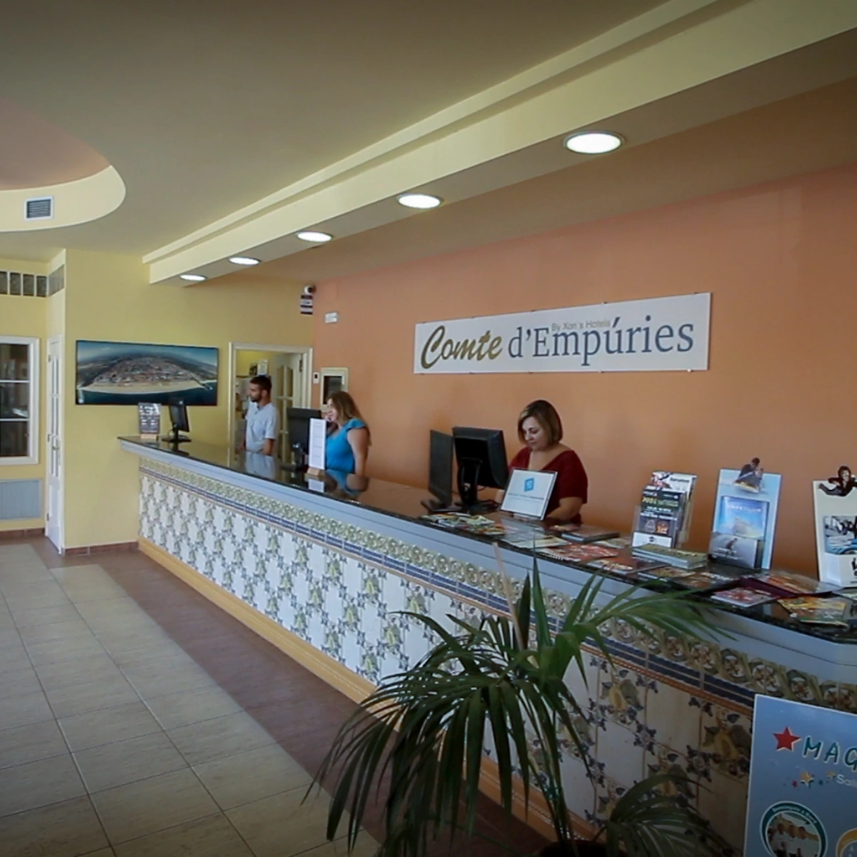 Recepci&oacute;n del Hotel Comte d'Emp&uacute;ries con personal atendiendo.