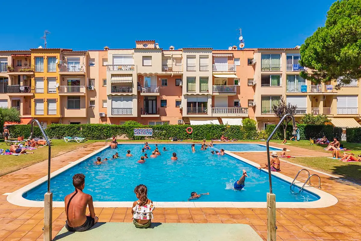 Personas disfrutando de una piscina al aire libre junto a edificios de apartamentos.