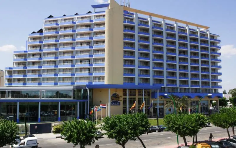 Edificio de hotel alto con balcones y banderas al frente.