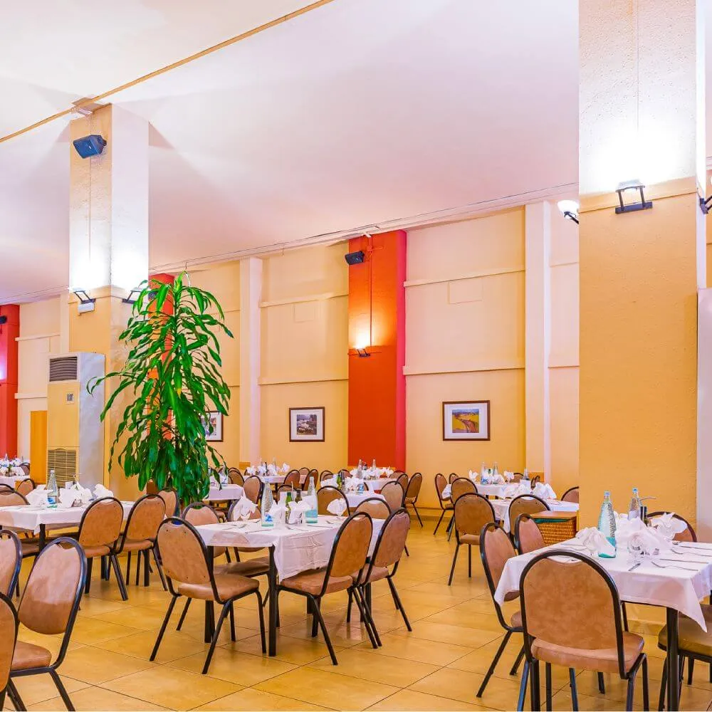 Restaurante con mesas listas, plantas y paredes multicolores.