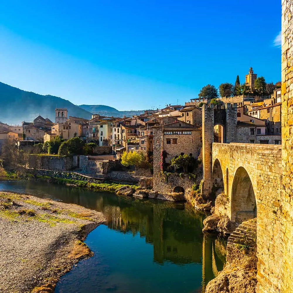 Puente medieval sobre un r&iacute;o en un pintoresco pueblo bajo cielo azul.