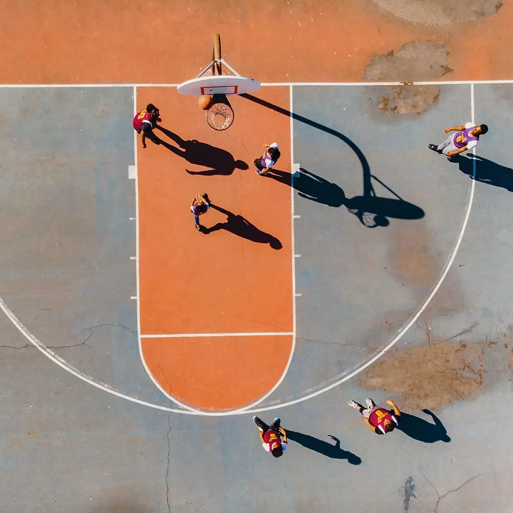 Jugadores de baloncesto visto desde arriba en una cancha al aire libre.