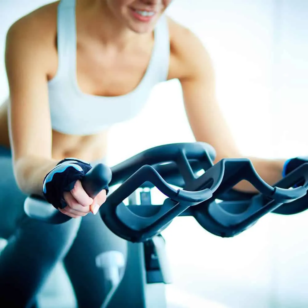 Mujer pedaleando en bicicleta est&aacute;tica durante ejercicio en el gimnasio.