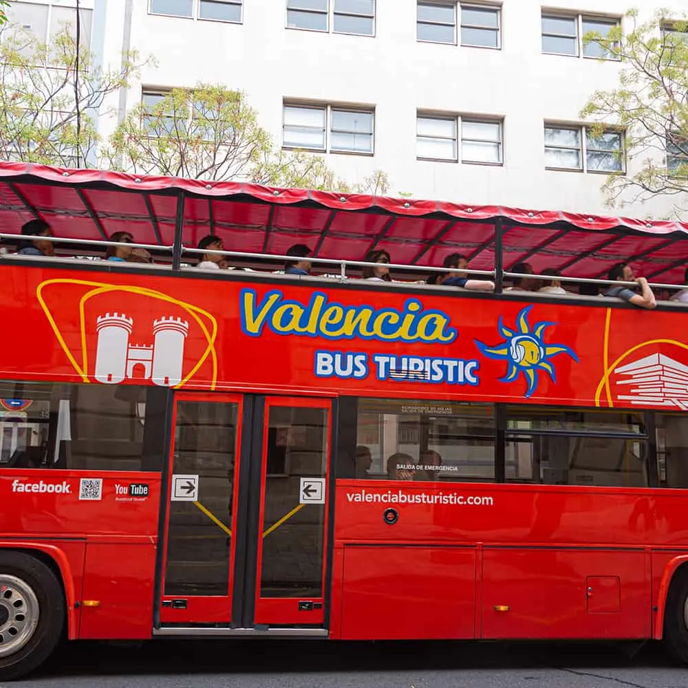 Autob&uacute;s tur&iacute;stico rojo de Valencia con techo abierto y pasajeros.