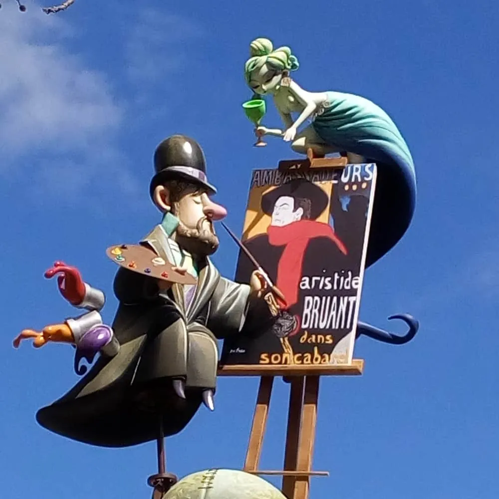 Estatuas caricaturescas de un pintor y una mujer sobre un cartel.