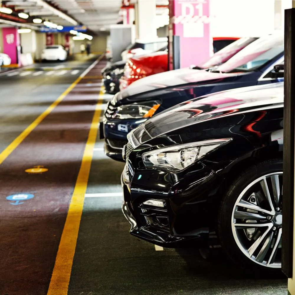 Coches estacionados en fila dentro de un aparcamiento cubierto.