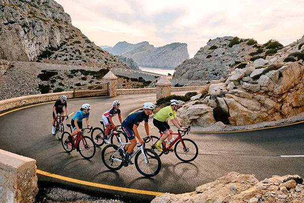 Ciclistas pedalean en una carretera monta&ntilde;osa con paisajes rocosos.