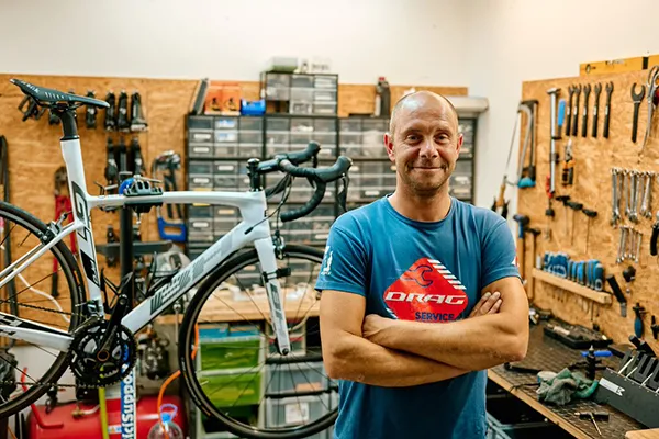 Persona en un taller de bicicletas con una bici en un soporte.
