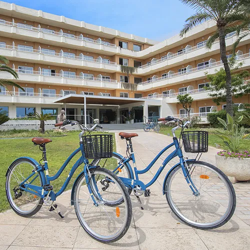 Dos bicicletas azules frente a un edificio hotelero con balcones m&uacute;ltiples.