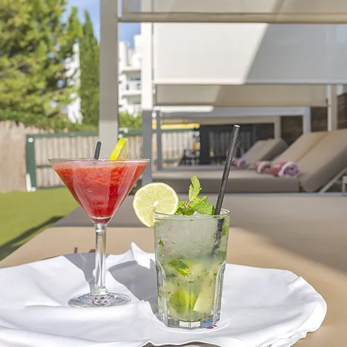 C&oacute;cteles en una terraza junto a tumbonas en un d&iacute;a soleado.