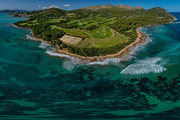 Isla verde con campos de golf rodeada por un mar turquesa.