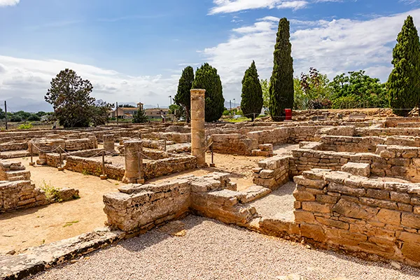 Ruinas romanas al aire libre bajo un cielo parcialmente nublado.