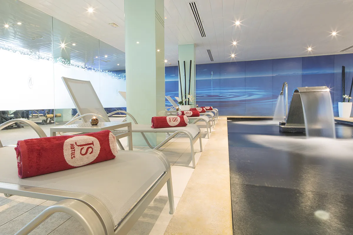 Tumbonas junto a una piscina interior con toallas rojas enrolladas.