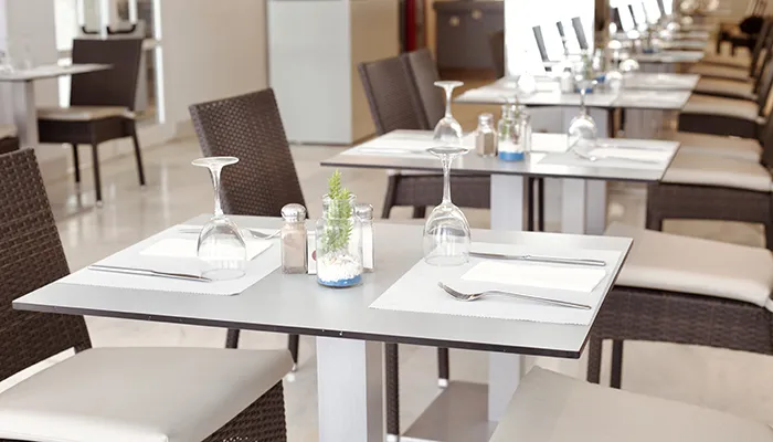 Restaurante con mesas elegantes y cubiertos listos para comensales.