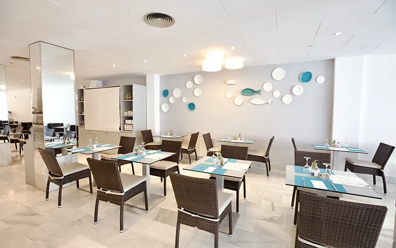 Comedor moderno con sillas de mimbre y decoraci&oacute;n minimalista en la pared.