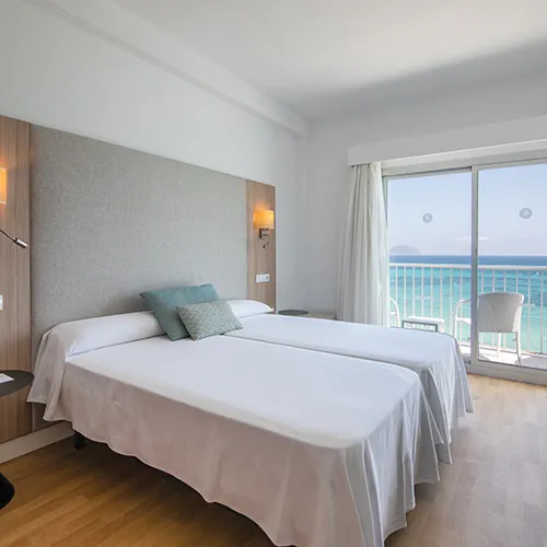 Habitaci&oacute;n con dos camas y vista al mar desde el balc&oacute;n.