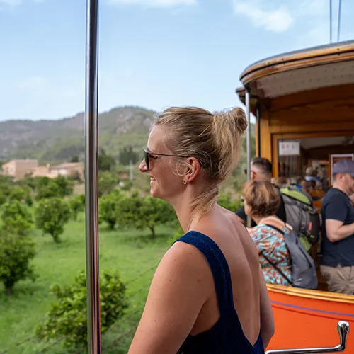 Persona disfrutando de un viaje en tranv&iacute;a con paisaje de fondo.
