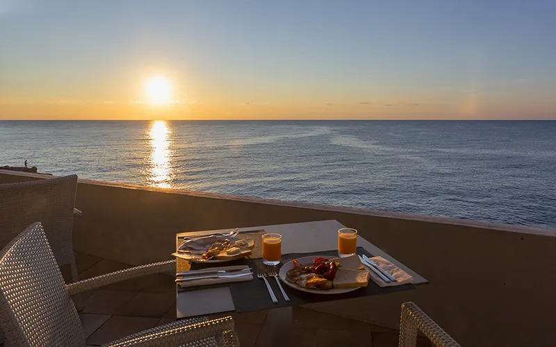 Desayuno en una mesa al borde del mar durante un amanecer.