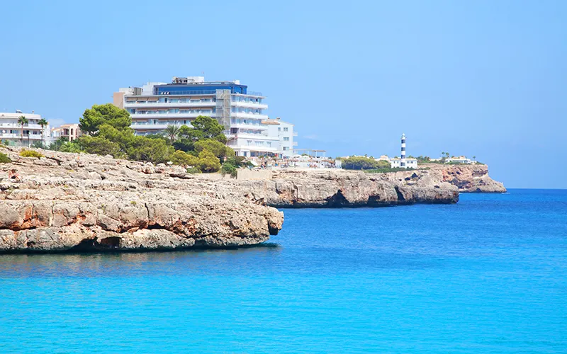 Acantilado con edificio y mar azul claro bajo cielo despejado.