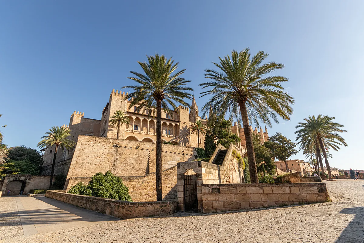 Castillo de piedra con palmeras y cielo despejado.