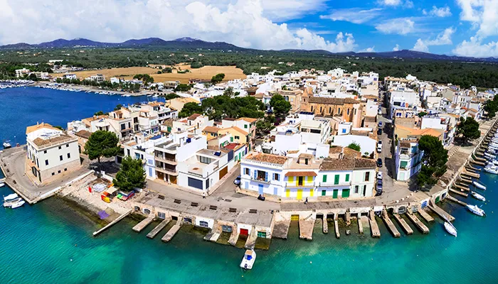 Vista a&eacute;rea de un pueblo costero con casas blancas y puerto deportivo.