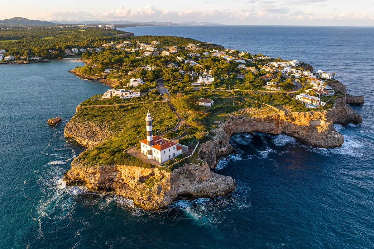 Costa con faro y casas en un acantilado junto al mar.