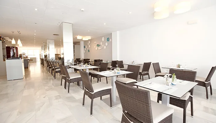 Restaurante moderno y luminoso con mesas vac&iacute;as y decoraci&oacute;n minimalista.