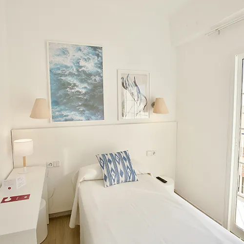 Habitaci&oacute;n moderna y luminosa con cama individual y arte en la pared.