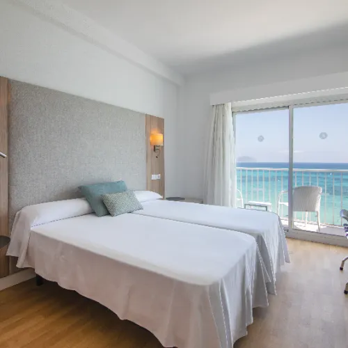 Habitaci&oacute;n de hotel con vista al mar desde el balc&oacute;n.