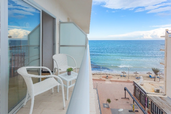 Balc&oacute;n con sillas blancas y vista al mar en un d&iacute;a soleado.