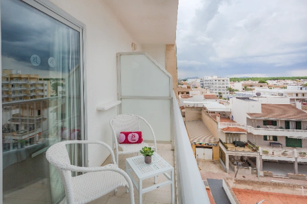 Balc&oacute;n con sillas y mesa vista a la ciudad bajo cielo nublado.