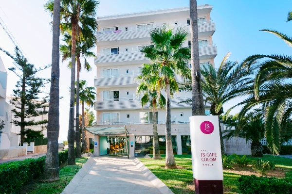 Edificio de hotel con palmeras y cartel que dice "JS Cape Colom".