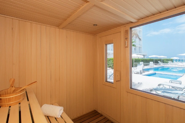 Sauna de madera con ventana que muestra una piscina al aire libre.
