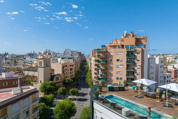 Vista a&eacute;rea de una ciudad con edificios, piscina en azotea y cielo despejado.