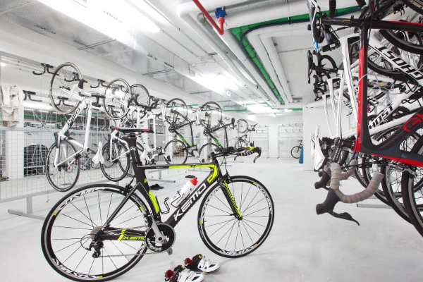 Sala blanca llena de bicicletas colgadas y una bicicleta de carreras en el suelo.