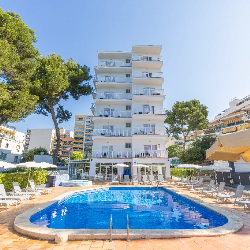 Edificio con piscina al aire libre rodeado de &aacute;rboles y sombrillas en un d&iacute;a soleado.
